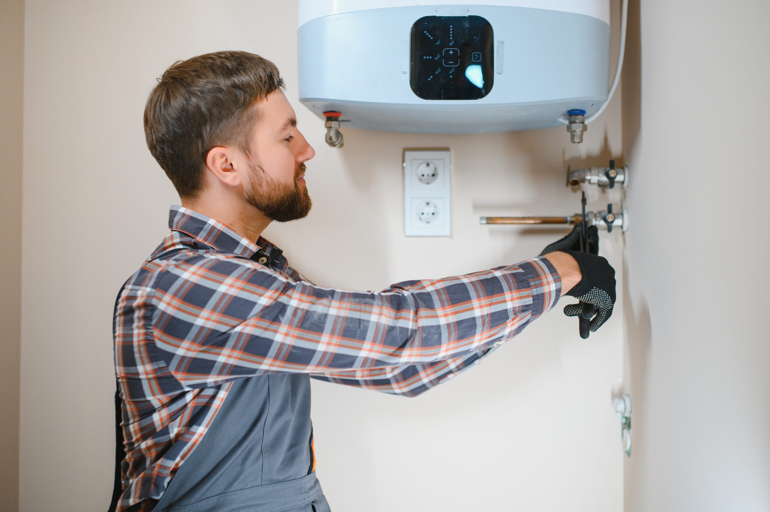 Professional plumber checking a boiler and pipes, boiler service concept.